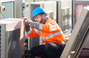 A tech examines an HVAC unit. If you wonder "What do mechanical services entail?" call Merit Mechanical Service!