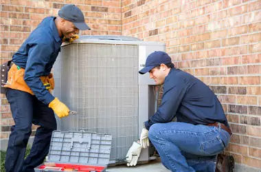 HVAC techs are seen performing service on a unit. Merit Mechanical performs commercial AC service in Peoria and Bloomington areas.