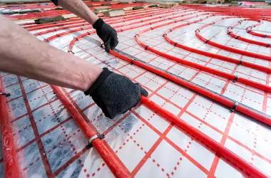 A worker is seen installing underfloor tubing. Merit Mechanical installs Geothermal Heating and Cooling in Peoria IL.